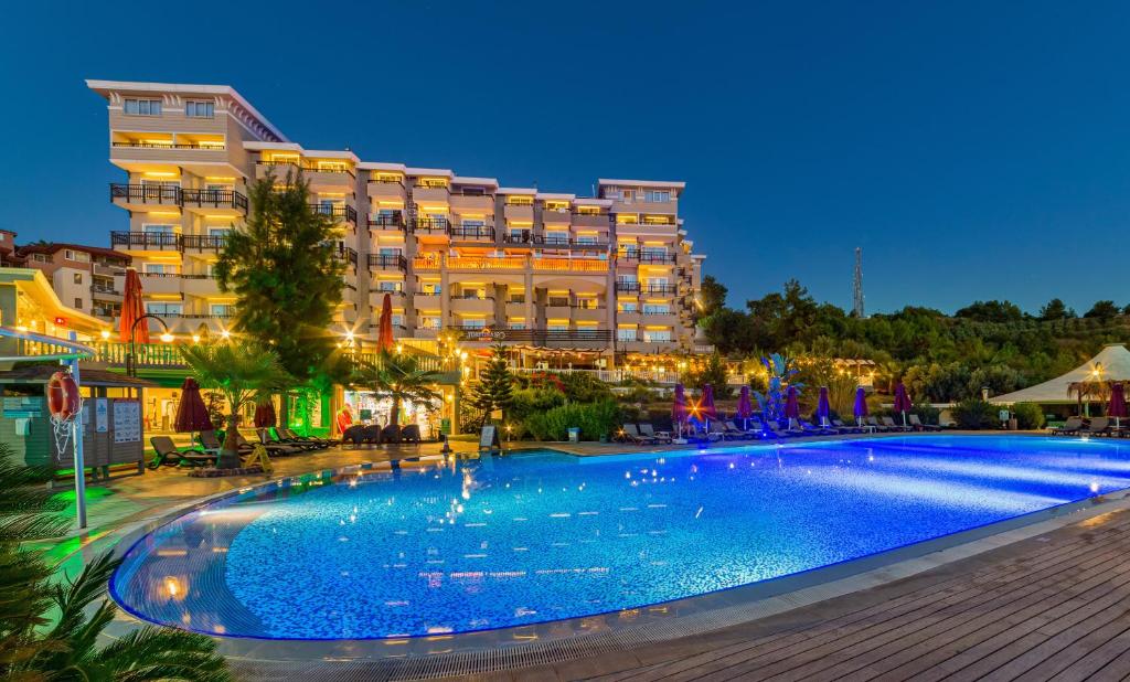 a hotel with a large swimming pool at night at Justiniano Deluxe Resort in Okurcalar