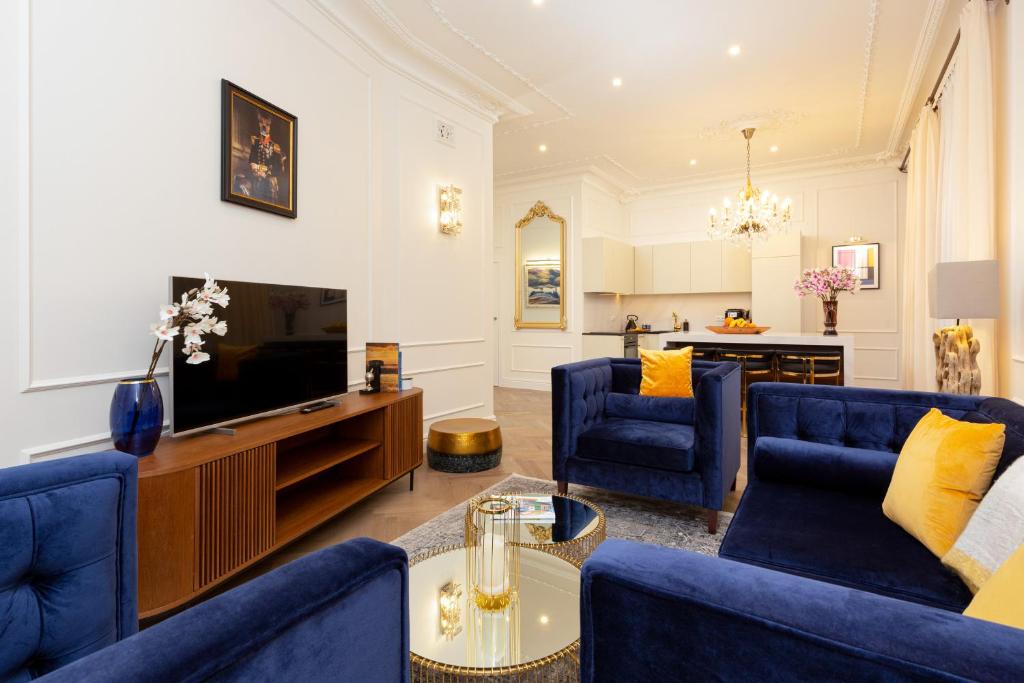 un salon avec des chaises bleues et une télévision dans l'établissement Royal Apartment Kopernika by Renters Prestige, à Varsovie