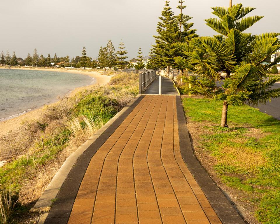 a brick walkway next to a beach with trees at Port Vincent Motel & Apartments in Port Vincent