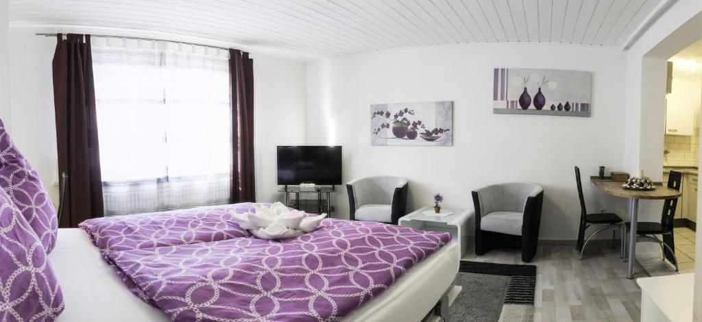 1 dormitorio con cama morada, mesa y sillas en Apart-2-OG-Nr1, en Darmstadt