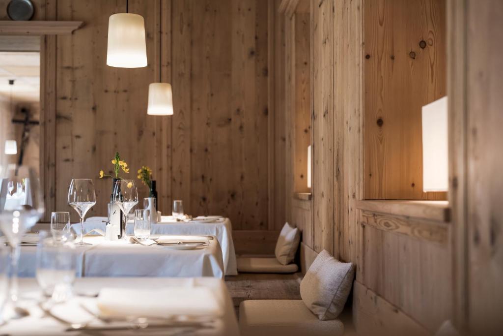 a dining room with two tables with white tablecloths at Adler Spa Resort Dolomiti in Ortisei