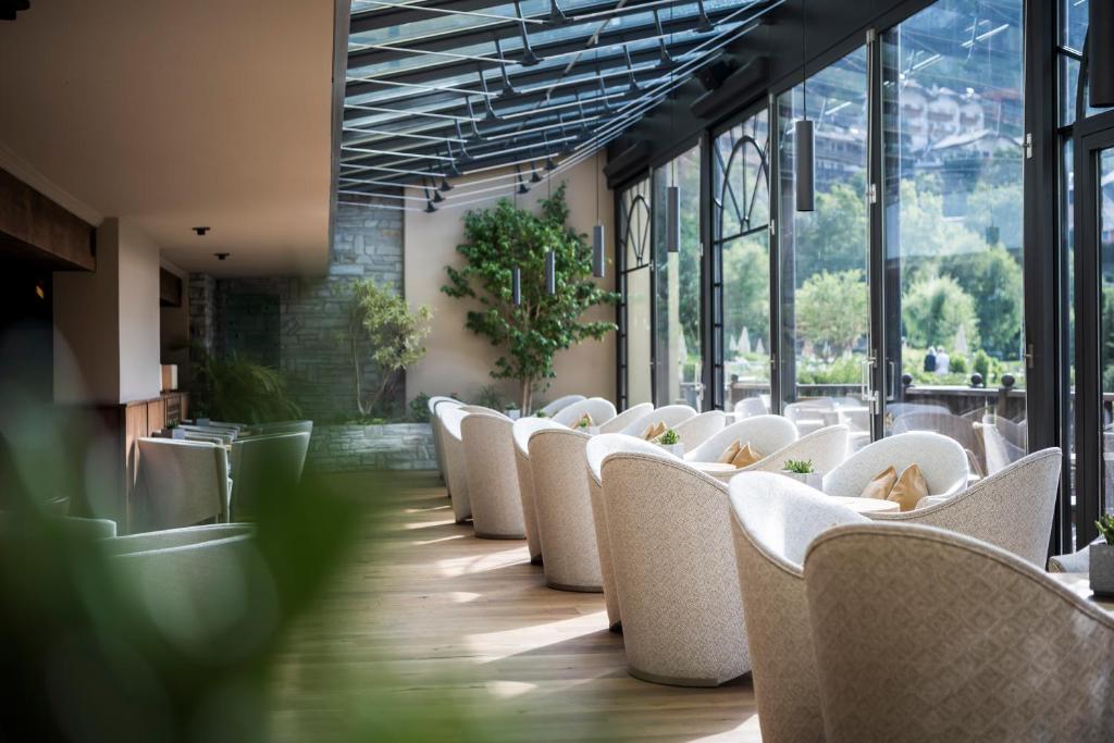 a row of white chairs in a room with windows at Adler Spa Resort Dolomiti in Ortisei