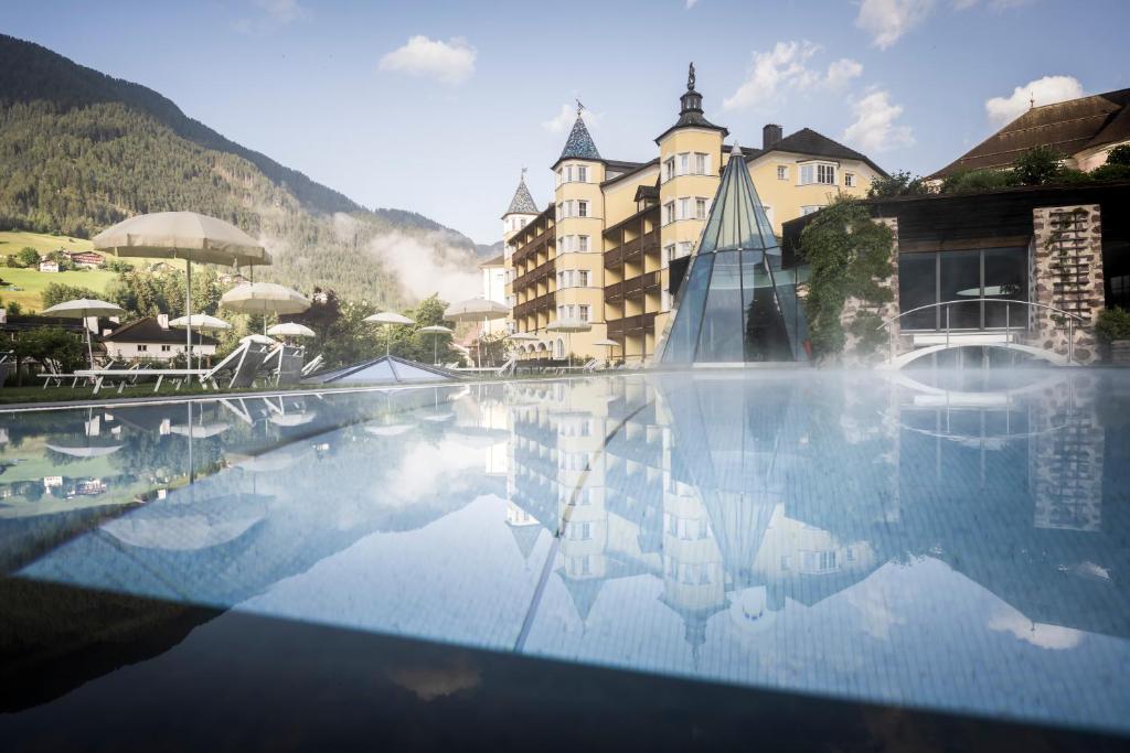 a hotel with a swimming pool in front of a building at Adler Spa Resort Dolomiti in Ortisei