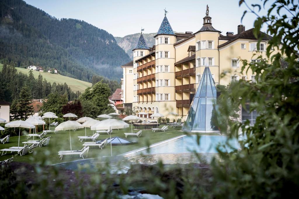 a large building with a clock tower in the middle of it at Adler Spa Resort Dolomiti in Ortisei