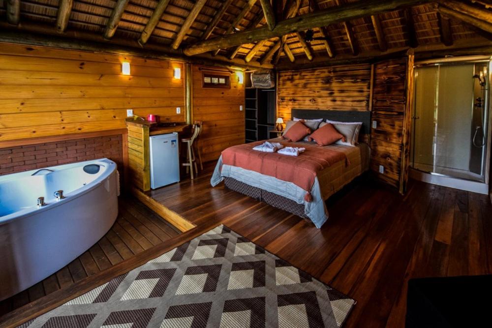 a bedroom with a bed and a tub in a cabin at Refugio monte itapeva in Torres