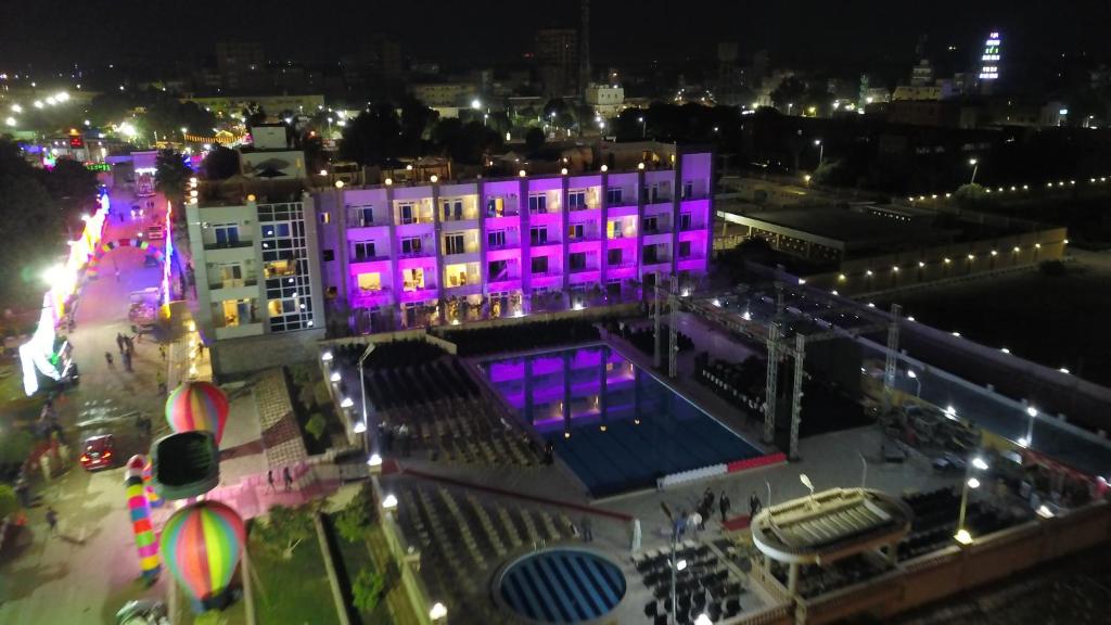 um edifício com luzes roxas numa cidade à noite em Jewel Assiut Hotel em Asyut