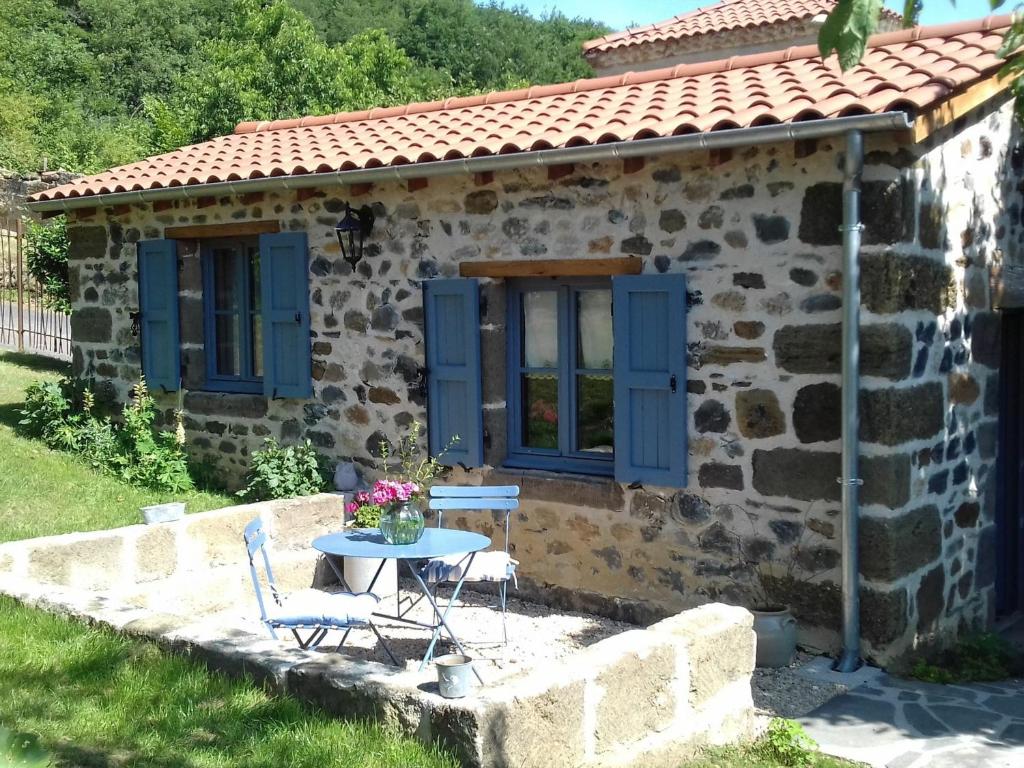 ein kleines Steinhaus mit blauen Fenstern und einem Tisch in der Unterkunft Gîte Langeac, 2 pièces, 2 personnes - FR-1-582-74 in Langeac
