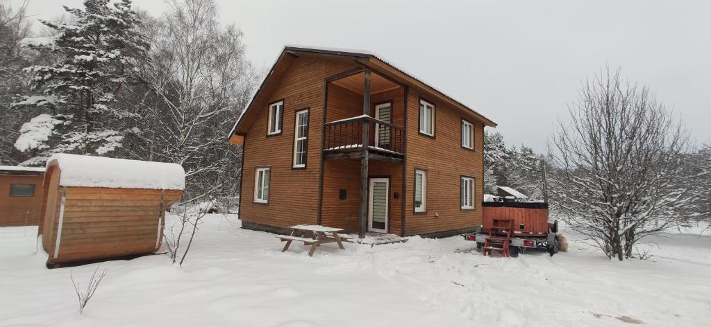 una gran casa de madera en la nieve con un banco en Igor House, en Jūrmala