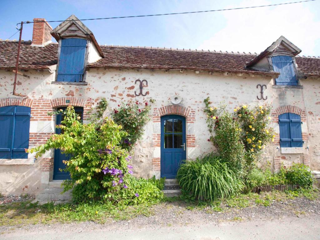 una antigua casa de piedra con puertas azules y flores en Gîte Communauté de communes Brenne - Val de Creuse-Rosnay, 5 pièces, 8 personnes - FR-1-591-141 en Rosnay