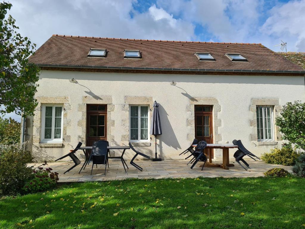 un patio con sillas y una sombrilla frente a una casa en Gîte Chailly-en-Gâtinais, 5 pièces, 8 personnes - FR-1-590-7, en Chailly-en-Gâtinais