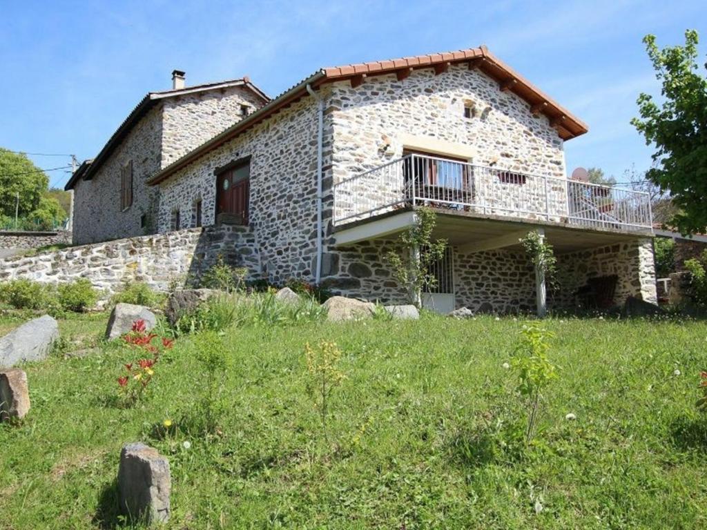 a stone house with a balcony on a field at Grange restaurée avec terrasse et wifi à La Bastide - FR-1-582-178 in Retournac