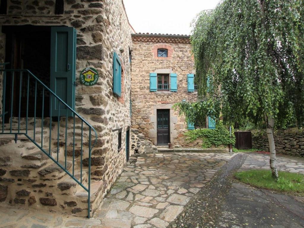 um edifício de pedra com uma porta e uma árvore em Gîte Villeneuve-d'Allier, 6 pièces, 10 personnes - FR-1-582-183 em Villeneuve-dʼAllier
