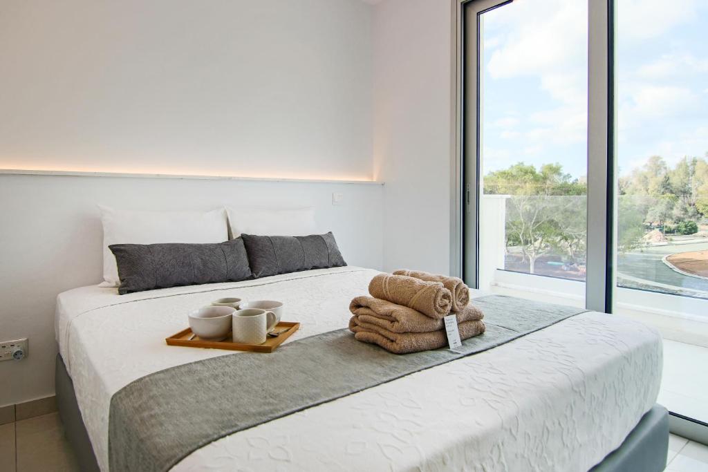 ein Schlafzimmer mit einem Bett mit einem Tablett mit zwei Tassen und einem Teddybär in der Unterkunft Phaedrus Living - Seaside Executive Flat Harbour 208 in Paphos