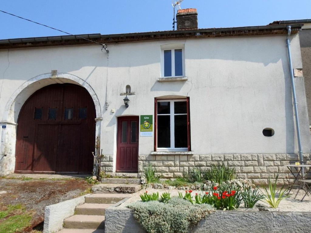 a white house with a brown door and flowers at Gîte Breuvannes-en-Bassigny, 3 pièces, 5 personnes - FR-1-611-44 in Breuvannes