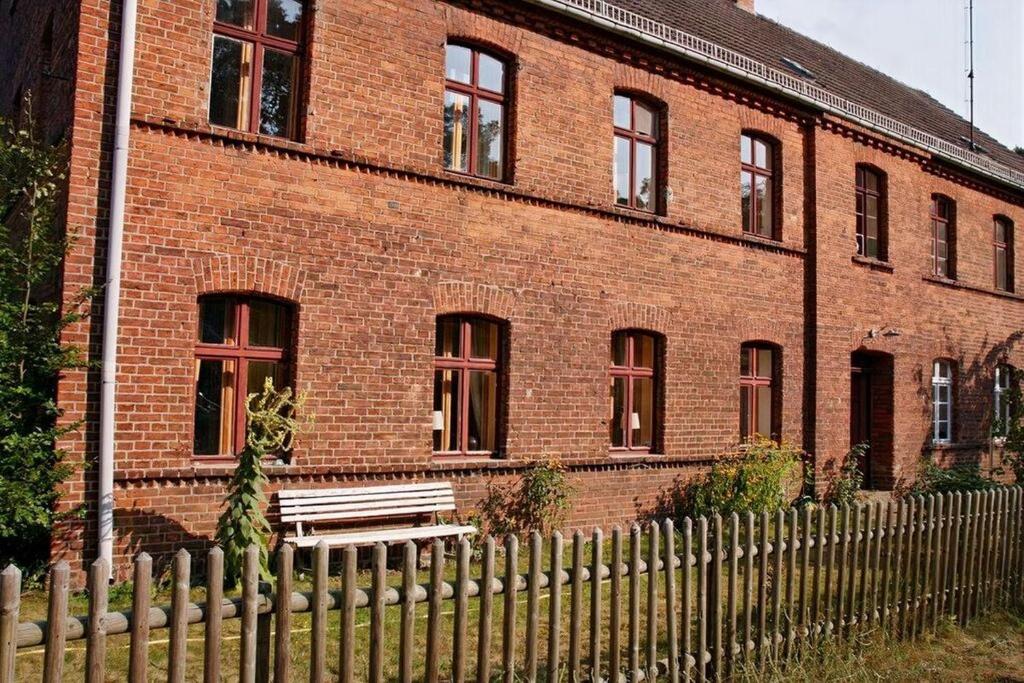 un edificio in mattoni con una recinzione di legno di fronte ad esso di Ferienwohnung Am Roten Schloss a Glashütte