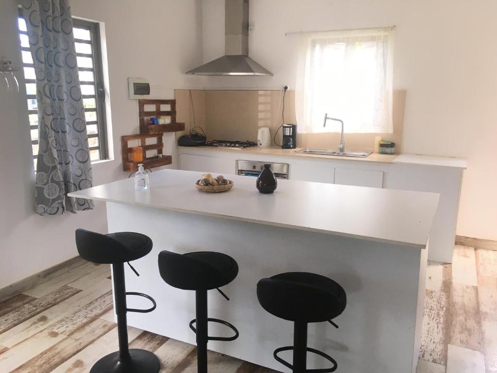 eine Küche mit einer weißen Theke und Stühlen in der Unterkunft O soleil in Albion