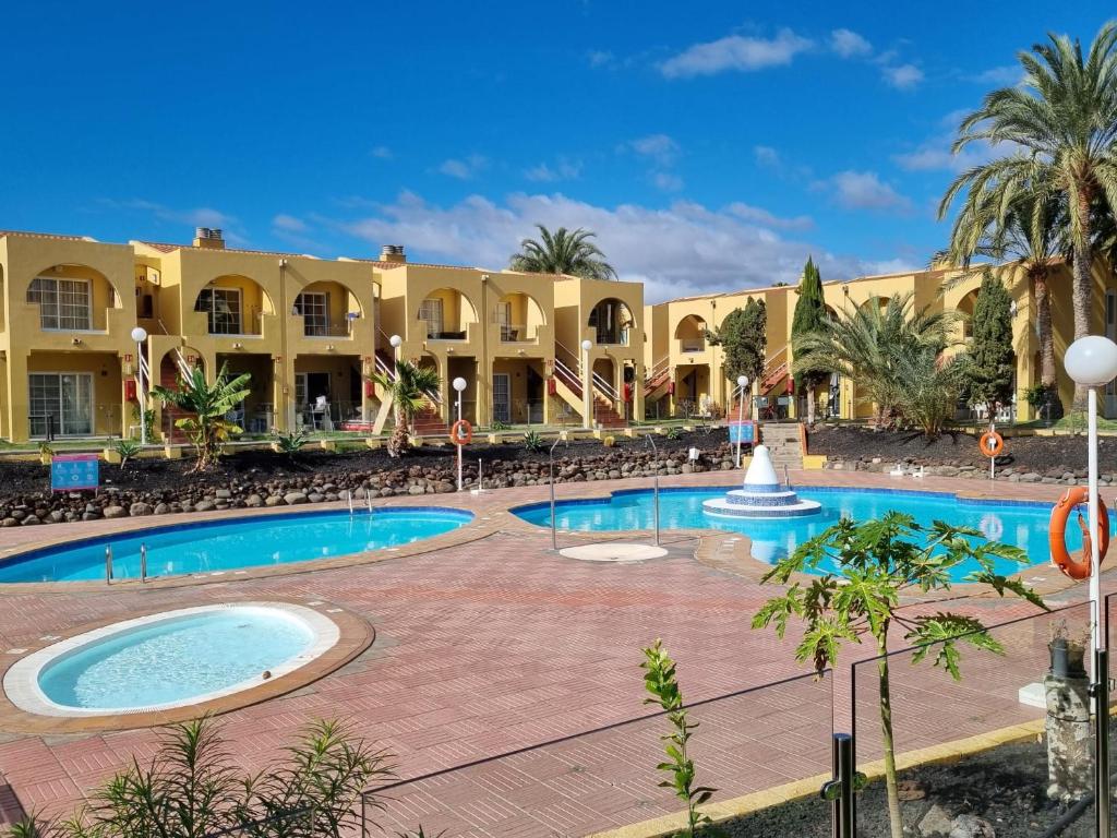 a resort with a swimming pool and palm trees at Maspalomas tisalaya park in Maspalomas