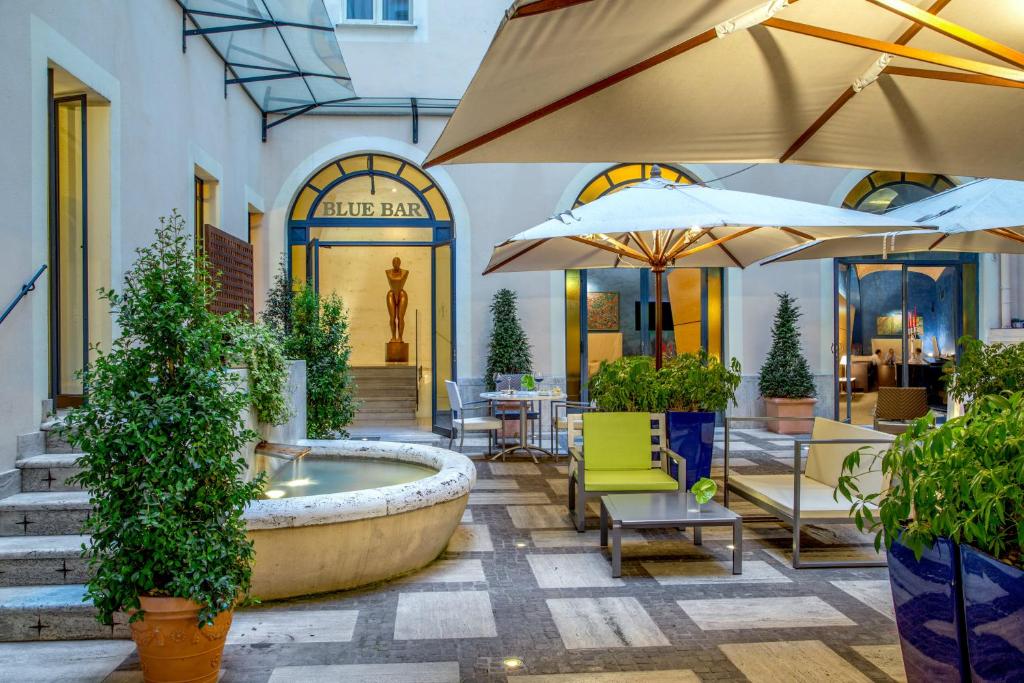 a patio with a fountain and tables and umbrellas at UNAWAY Hotel Empire Roma in Rome