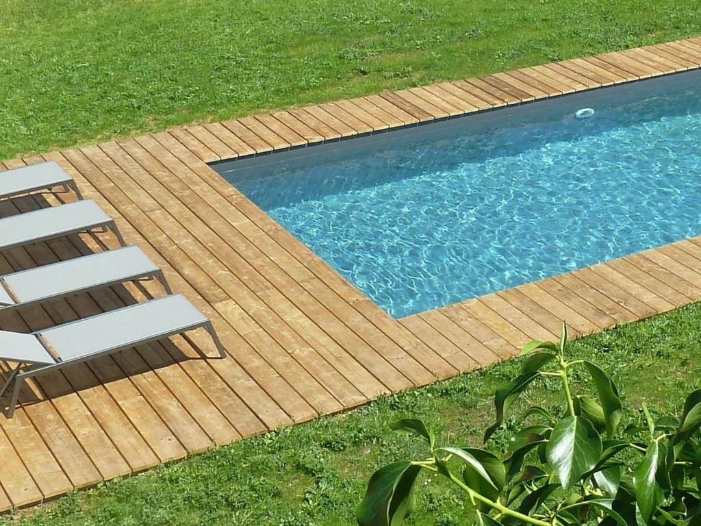 a swimming pool with two chairs next to a wooden deck at Grande maison rénovée, piscine, 4 chambres, vaste terrain, près piste cyclable et pêche, Wi-Fi inclus - FR-1-426-408 in Fontenay-le-Comte