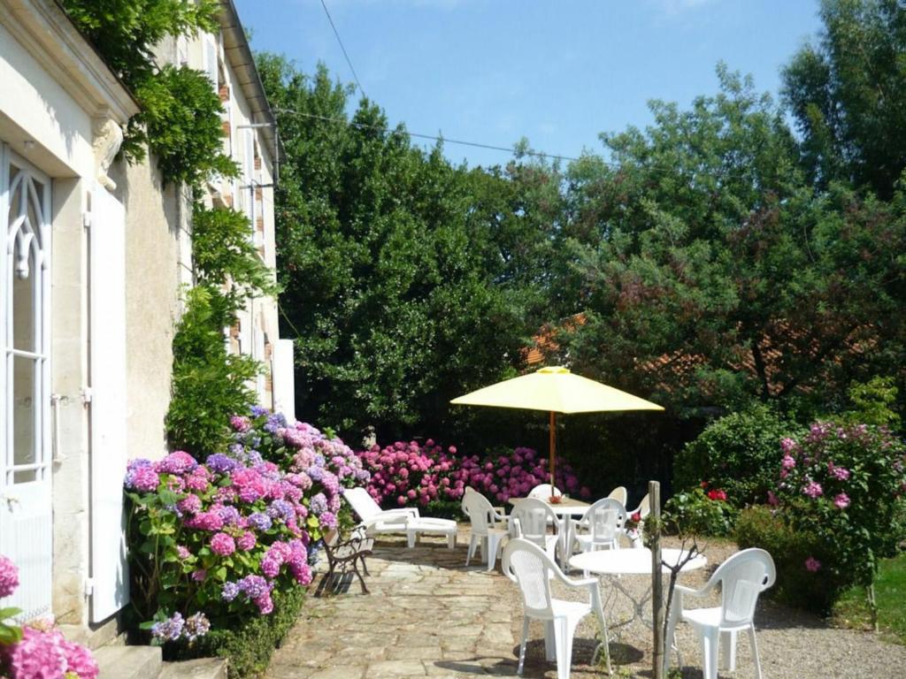 eine Terrasse mit weißen Tischen, Stühlen und Blumen in der Unterkunft Gîte Le Champ-Saint-Père, 4 pièces, 8 personnes - FR-1-426-239 in Le Champ-Saint-Père