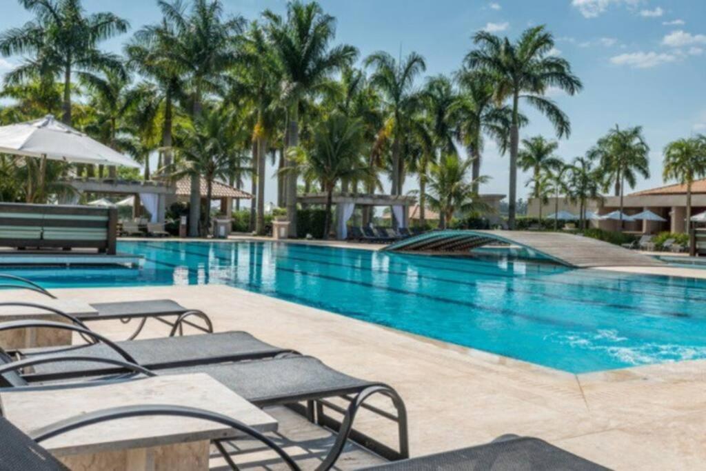 a pool at a resort with chairs and palm trees at Resort&House,4 Quartos, 8 pessoas, Beach tenis, Bike, Golfe, Pesca, Ar, Wifi fibra, TV a cabo e Lareira in Santa Bárbara do Rio Pardo