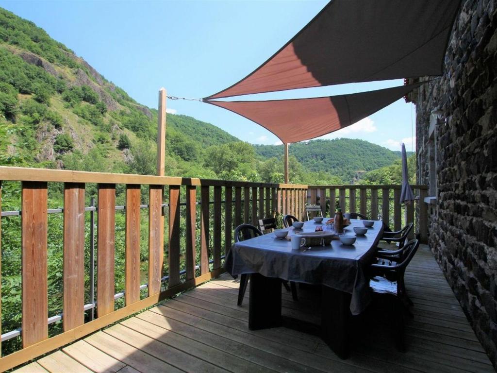 un tavolo su una terrazza in legno con ombrellone di Gîte Saint-Julien-des-Chazes, 5 pièces, 9 personnes - FR-1-582-17 a Saint-Julien-des-Chazes