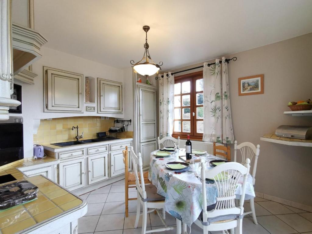 una cocina con mesa y sillas y una cocina con armarios blancos. en Gîte Saint-Germain-Laprade, 4 pièces, 6 personnes - FR-1-582-322 en Saint-Germain-Laprade