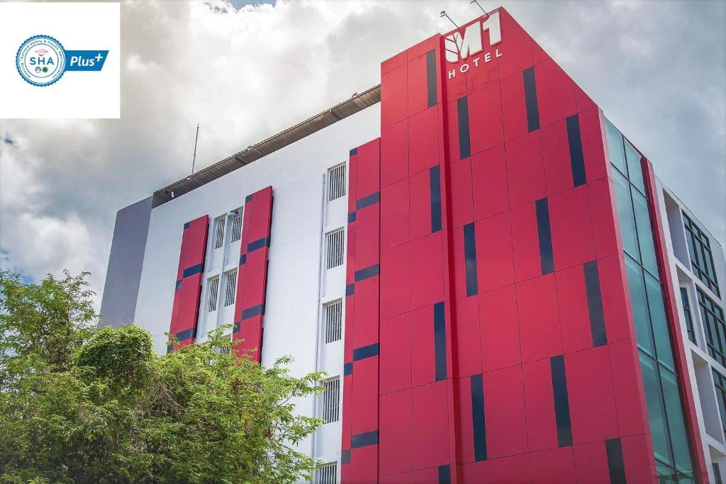 un edificio rojo con un cartel en el costado en M1 Hotel en Nakhon Si Thammarat