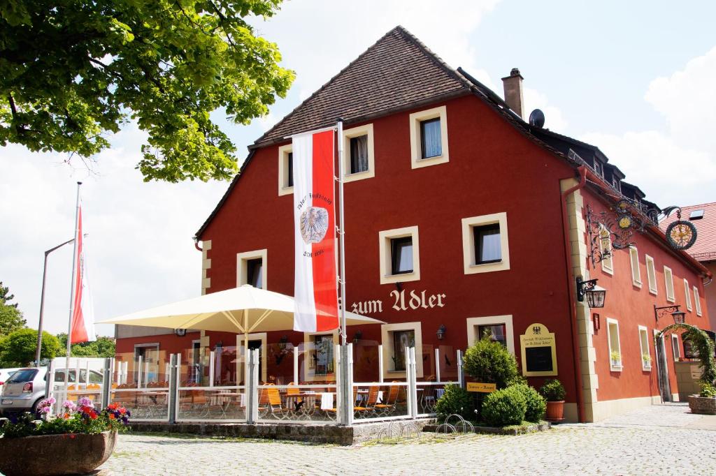 ein rotes Gebäude mit einem Restaurant davor in der Unterkunft Gasthof Adler in Schillingsfürst