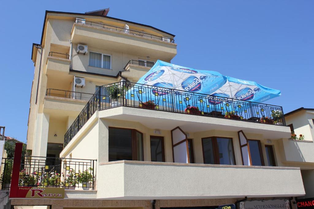 a building with a balcony with a blue banner on it at Hotel Radik in Sozopol