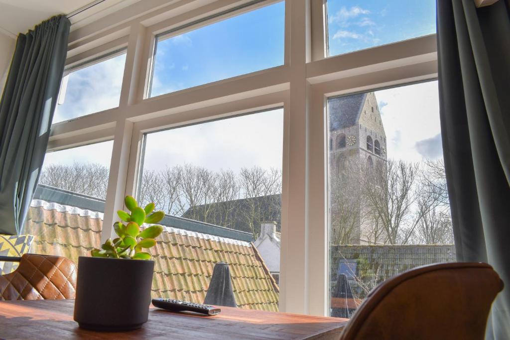 uma mesa com um vaso de planta na frente de uma janela em De Welvaart - Logement em Hollum