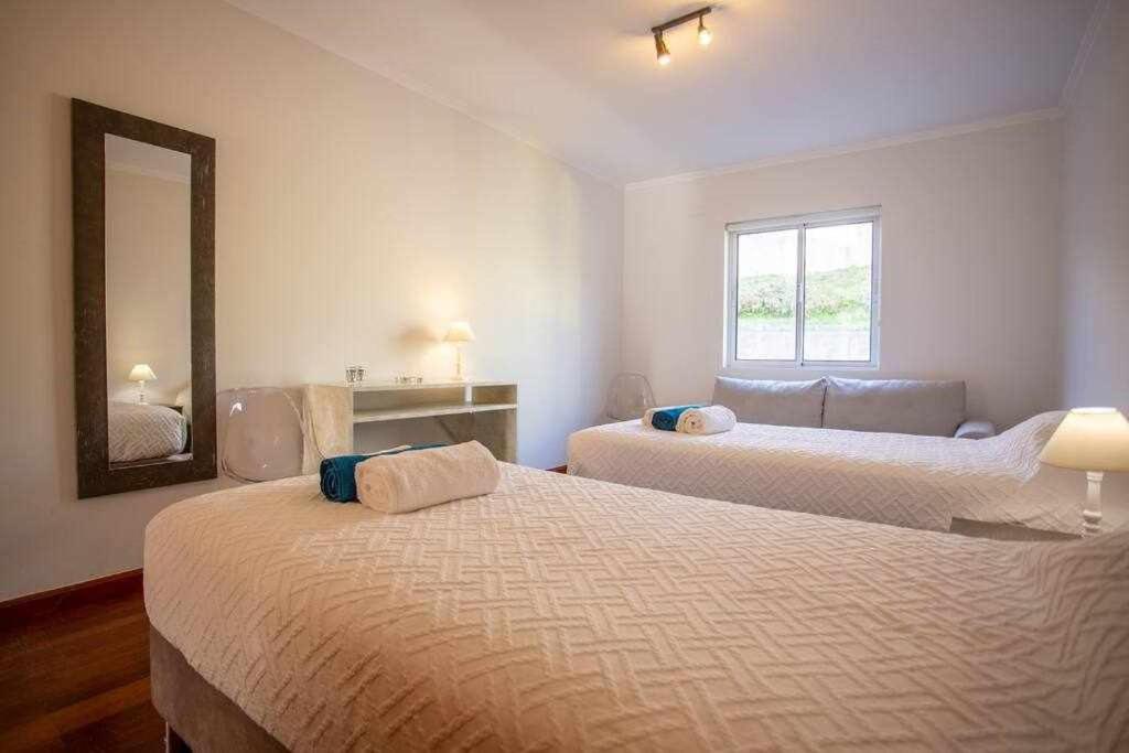 a bedroom with two beds and a mirror at Marina de Vila Franca do Campo in Vila Franca do Campo