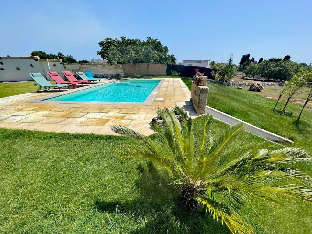 a villa with a swimming pool and a palm tree at Fiorillo Cottage in Gagliano del Capo