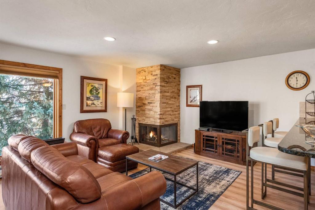a living room with a leather couch and a fireplace at Shadowbrook 205 in Snowmass Village