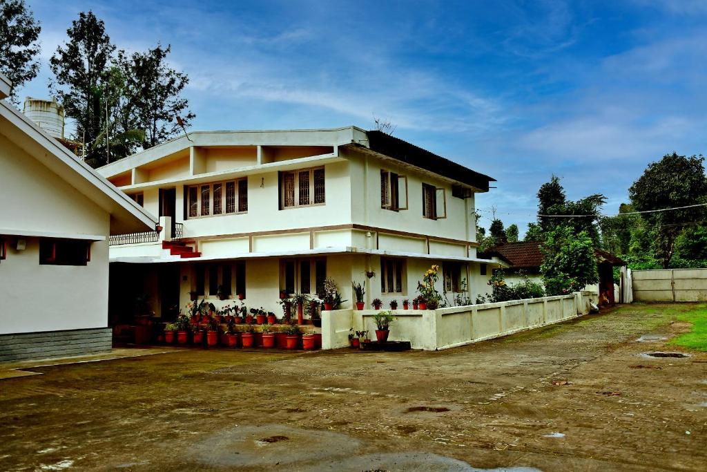 a white house with a lot of flowers in front of it at Thavihakklu Homestay 4BH, Kitchen, Coffee Estate in Chikmagalūr