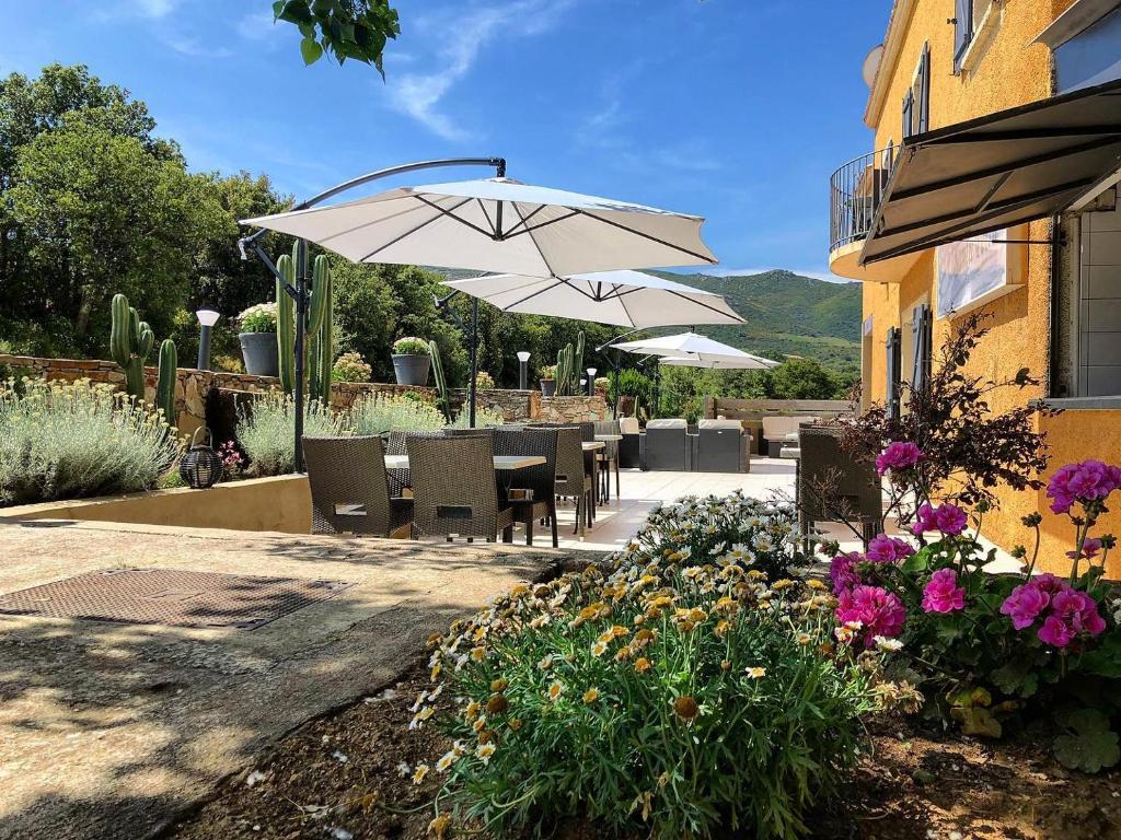 a patio area with a patio table and chairs at Hôtel - Restaurant U Santu Petru in Saint-Florent