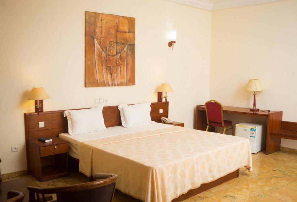 Hôtel Marbella في لوميه: غرفة نوم بسرير ودهان على الحائط