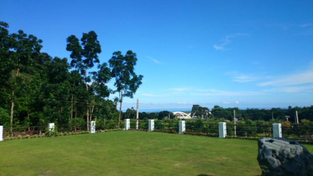 a large grassy field with a fence and trees at Li Wu Zuo Cun B&amp;B in Chongde