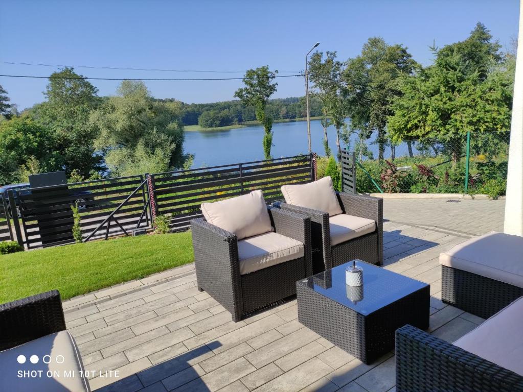 d'une terrasse avec des chaises et une vue sur la rivière. dans l'établissement New House Mazury, à Sorkwity