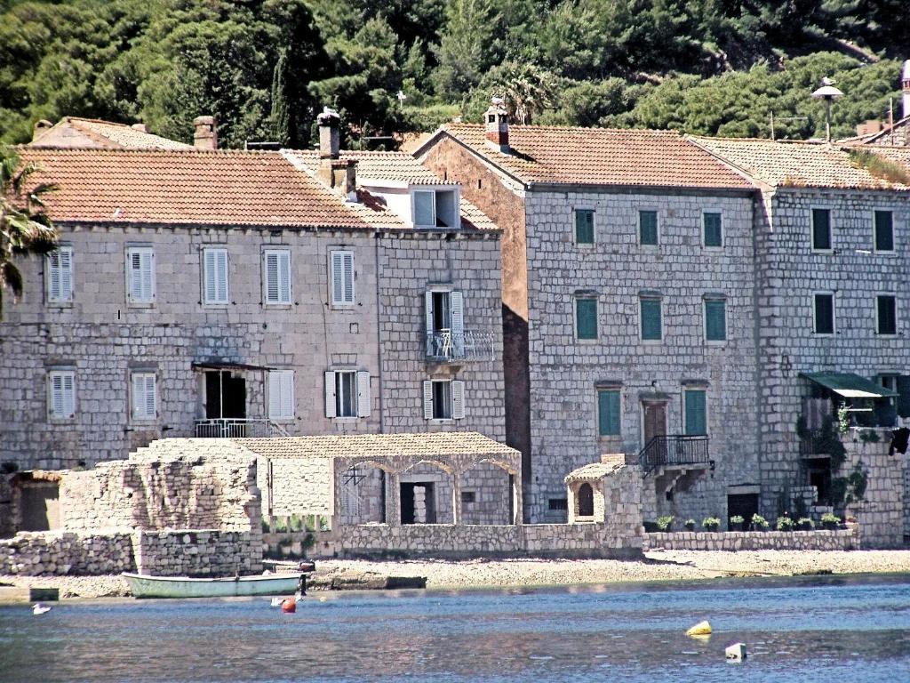 um grande edifício de pedra com um barco na água em Apartments Acalinović em Vis