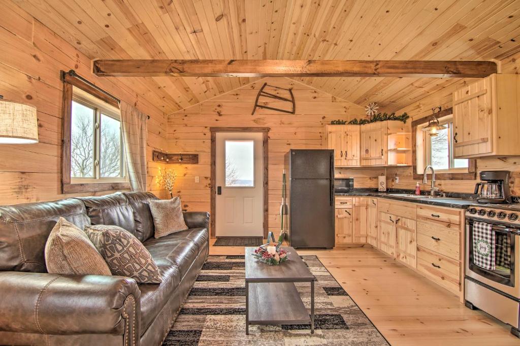 Una sala de estar con un sofá de cuero y una cocina. en Serene Views Quiet Farmhouse Cabin in Wisconsin!, en Blanchardville