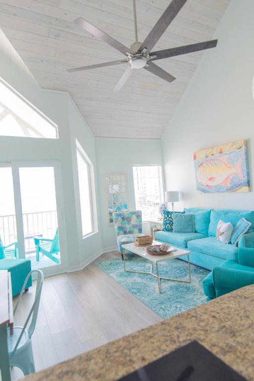 ein Wohnzimmer mit blauen Sofas und einem Deckenventilator in der Unterkunft Grand Beach Resort Penthouse 1 in Gulf Shores