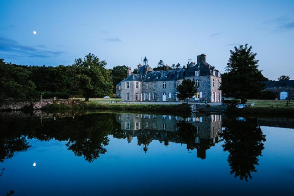 una grande casa seduta accanto a un corpo d'acqua di Domaine de la Motte-Basse a Le Gouray