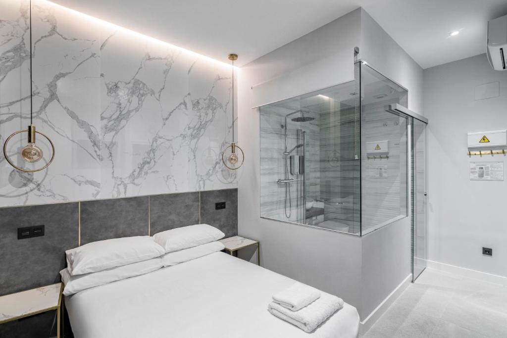 Schlafzimmer mit einem weißen Bett und einer Glasdusche in der Unterkunft EMBA ROOM in Madrid