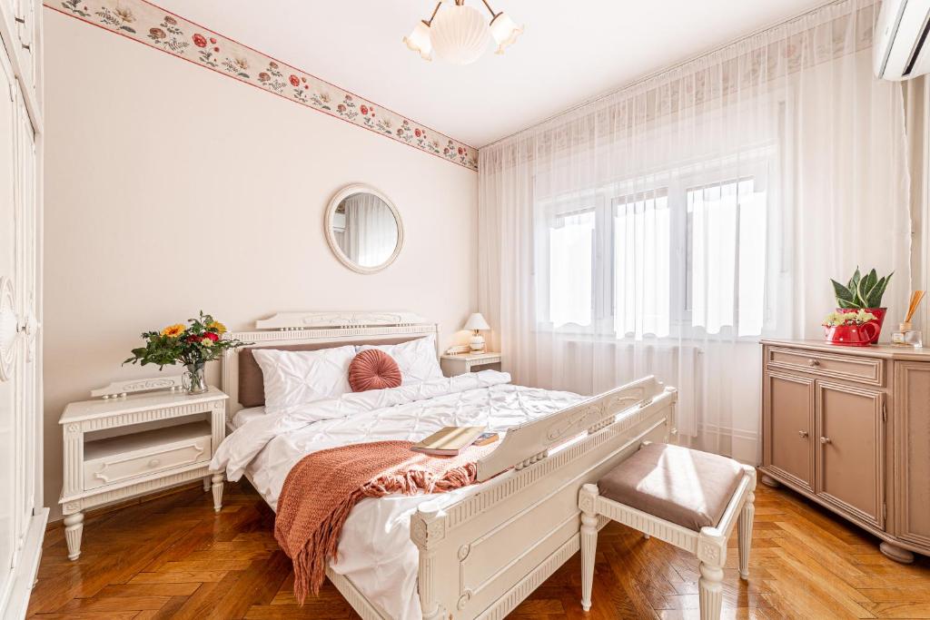 a white bedroom with a bed and a window at NALA Central Apartment in Arad