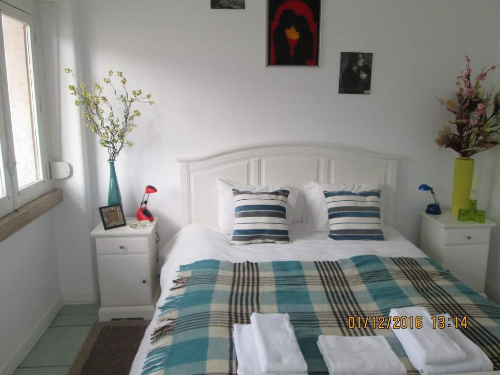 a bedroom with a white bed with striped sheets and pillows at Praça do Chile apartment in Lisbon