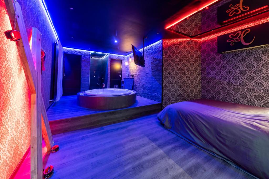 a bathroom with a tub and a bed in it at Cupidon Love Room in Vesoul