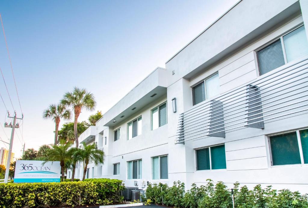 a white building with palm trees in front of it at 365 Ocean in Boca Raton