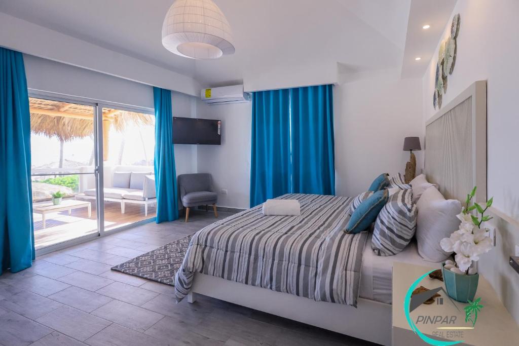 sypialnia z łóżkiem z niebieskimi zasłonami i balkonem w obiekcie Villa Blanca Beach Club w Punta Cana