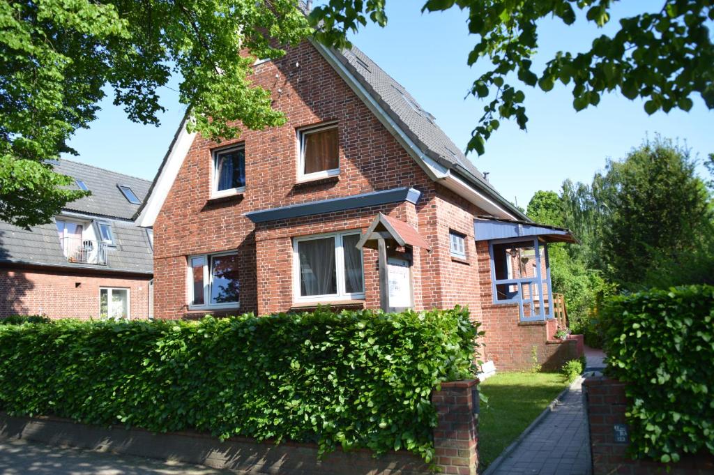 une maison en briques avec une haie devant elle dans l'établissement Arkadia Pension Norderstedt, à Norderstedt